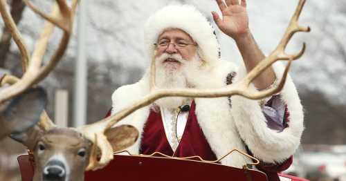 Santa Claus waves from a festive sleigh, with reindeer antlers in the foreground, set against a wintery backdrop.