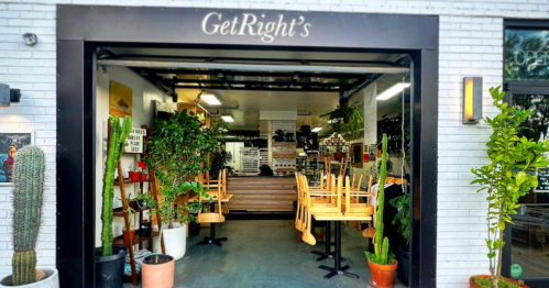 A cozy restaurant entrance with plants, empty chairs stacked on tables, and a welcoming sign reading "GetRight's."