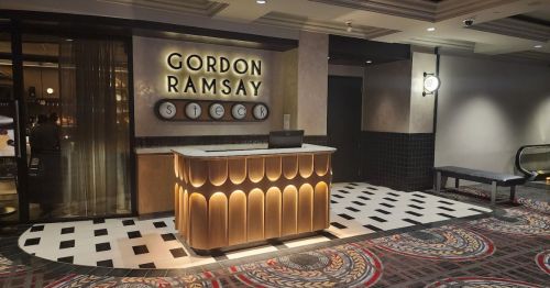 Entrance to Gordon Ramsay Steak, featuring a stylish reception desk and modern decor in a vibrant setting.