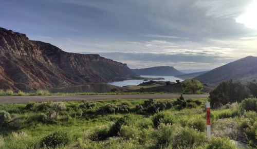 Scenic view of a lake surrounded by mountains and greenery under a cloudy sky.