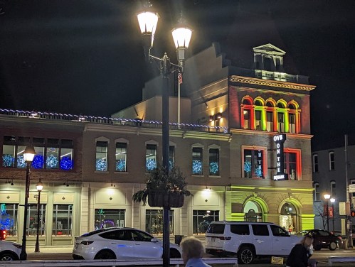 A brightly lit historic building at night, adorned with colorful lights and festive decorations.