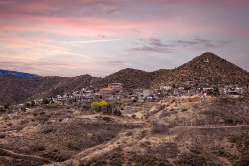 A scenic view of a mountainous landscape with a small town nestled among the hills under a colorful sky.