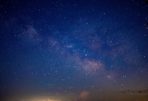 A stunning night sky filled with stars and the Milky Way, showcasing deep blues and scattered celestial bodies.
