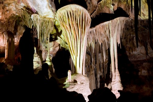 Stalactites and stalagmites in a colorful cave, illuminated by soft lighting, creating a dramatic natural formation.