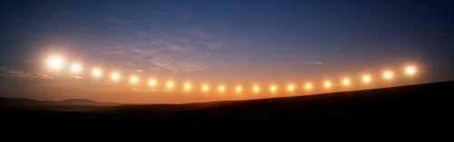 A sequence of sun positions in the sky, illustrating the passage of time during sunset over a landscape.