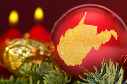 A red Christmas ornament featuring a gold silhouette of West Virginia, surrounded by festive greenery and candles.