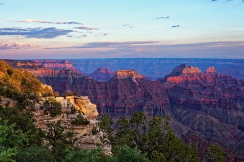 A stunning view of the Grand Canyon at sunset, showcasing layered rock formations and vibrant colors in the sky.