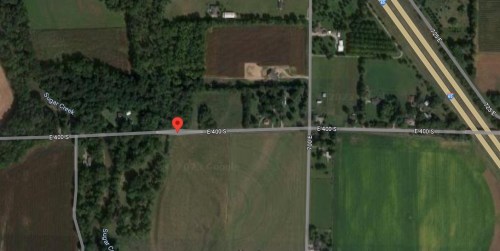 Aerial view of a rural area with roads, fields, and patches of trees, marked by a red pin on E400 S.