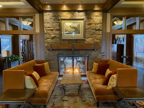 Cozy lounge area with two orange sofas, a coffee table, and a stone fireplace, creating a warm, inviting atmosphere.