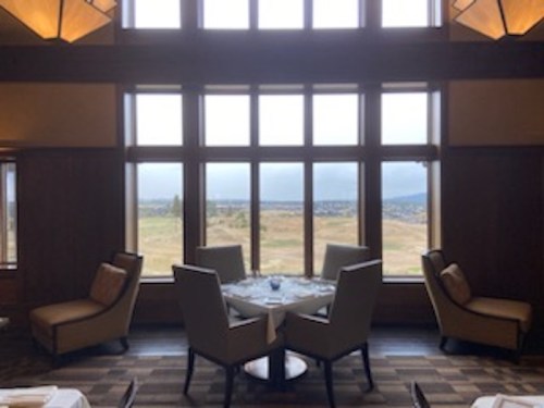 A cozy dining area with a round table and four chairs, featuring large windows overlooking a scenic landscape.