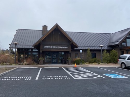 Lodging check-in building with a modern design, surrounded by landscaping and parking spaces.