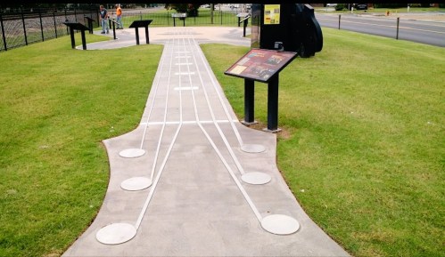 A concrete pathway designed to resemble a guitar, with musical notes and information signs nearby.