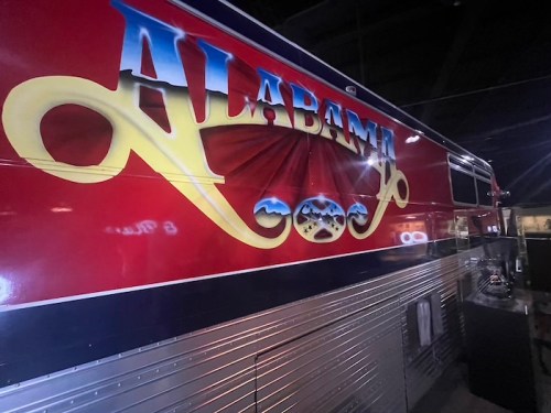 A colorful vintage bus with "ALABAMA" painted in bold letters on the side, featuring decorative designs.