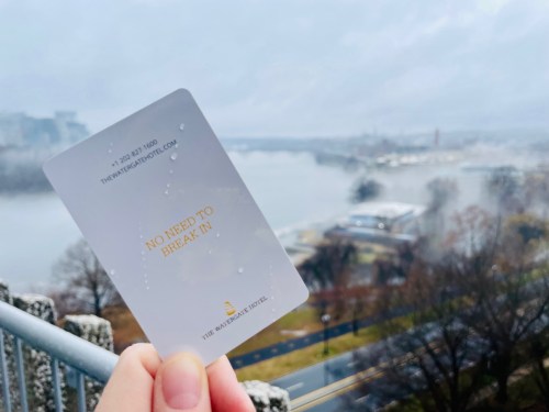 A hand holds a card with "NO NEED TO BREAK IN" against a misty river view.