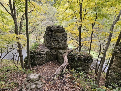 A rocky outcrop surrounded by vibrant autumn trees and a river in the background.