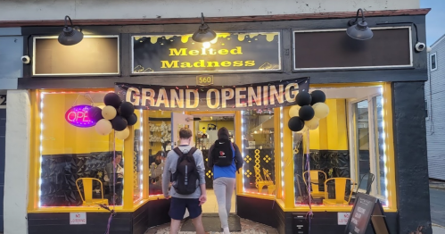 A storefront with a "Grand Opening" banner, balloons, and bright yellow decor, welcoming customers inside.