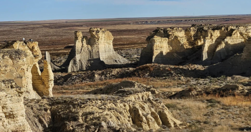 A vast landscape featuring unique rock formations and rugged terrain under a clear blue sky.