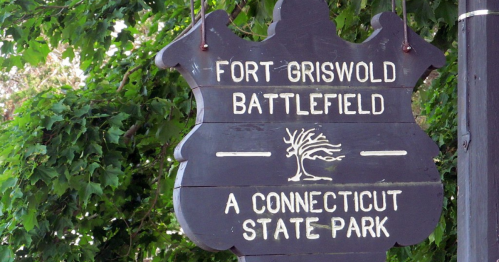 Sign for Fort Griswold Battlefield, a Connecticut State Park, surrounded by green foliage.