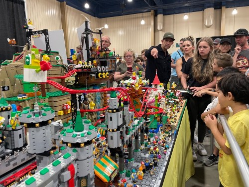 A large, detailed LEGO display with a crowd of people admiring it at an event.