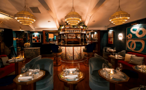 Elegant restaurant interior featuring a stylish bar, plush seating, and warm lighting, creating a cozy atmosphere.