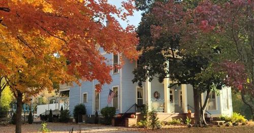 A charming blue house surrounded by vibrant autumn trees with orange and red leaves.