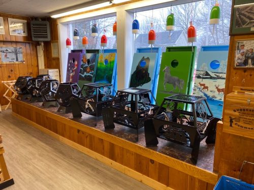A row of black display stands with colorful artwork behind them in a wooden interior space.