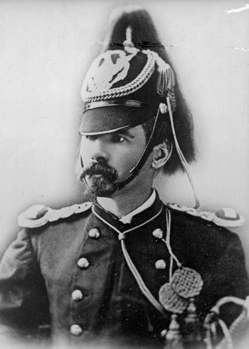 A historical black and white portrait of a man in a military uniform with a decorative hat and mustache.