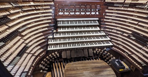 A large, intricate pipe organ console with numerous keys and buttons arranged in a curved design.