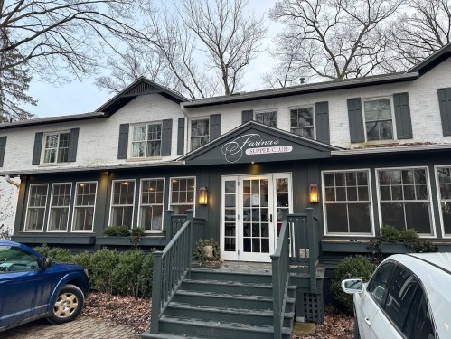 A charming two-story building with a sign reading "Farina's Supper Club," surrounded by trees and parked cars.