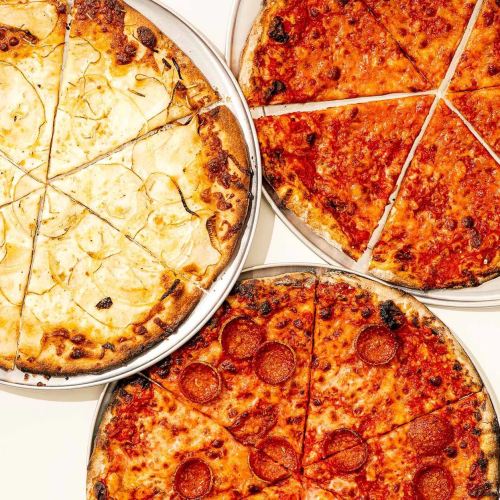 Three pizzas on metal trays: one with pepperoni, one with tomato sauce, and one topped with sliced potatoes.