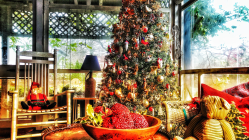 A cozy room with a decorated Christmas tree, a rocking chair, and festive cushions on a table.