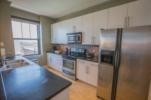 Modern kitchen with stainless steel appliances, white cabinets, and a large window offering natural light.