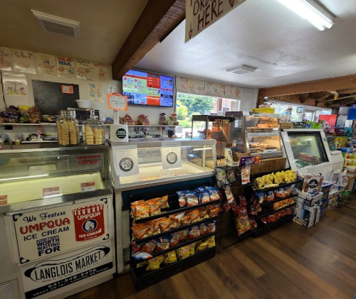 Interior of a market featuring ice cream displays, snacks, and a menu board on the wall. Bright and inviting atmosphere.