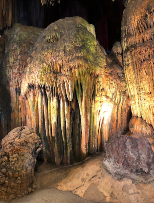 Stalactites and stalagmites in a dimly lit cave, showcasing unique rock formations and textures.