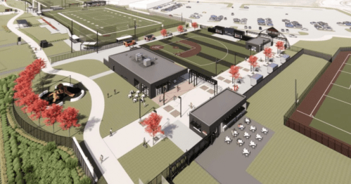 Aerial view of a sports complex featuring fields, courts, and a central building with outdoor seating and landscaping.