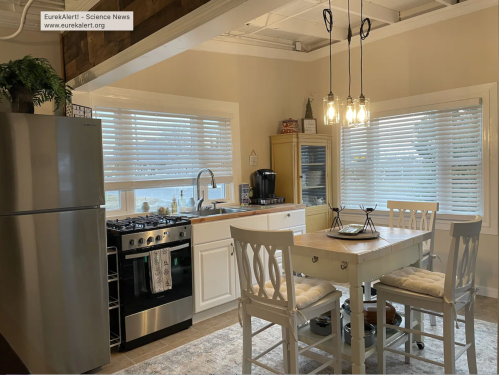 A modern kitchen featuring a stainless steel fridge, stove, white cabinets, and a dining table with chairs.