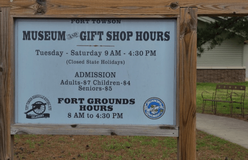 Sign displaying hours for the Fort Towson Museum and Gift Shop, including admission prices and holiday closures.