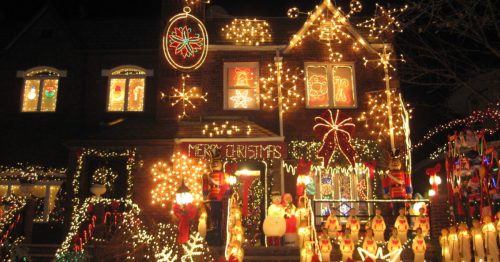 A brightly decorated house for Christmas, adorned with colorful lights, ornaments, and festive figures.