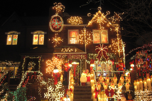 A festive house decorated with colorful Christmas lights, ornaments, and holiday figures, creating a cheerful holiday scene.