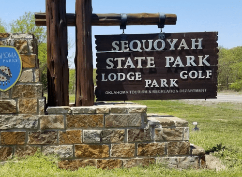 Sign for Sequoyah State Park, featuring Lodge, Golf, and Park, with a stone base and greenery in the background.