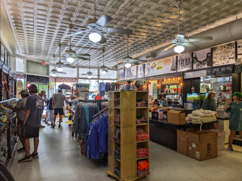A bustling retail store interior with shelves of clothing, fans, and customers browsing merchandise.