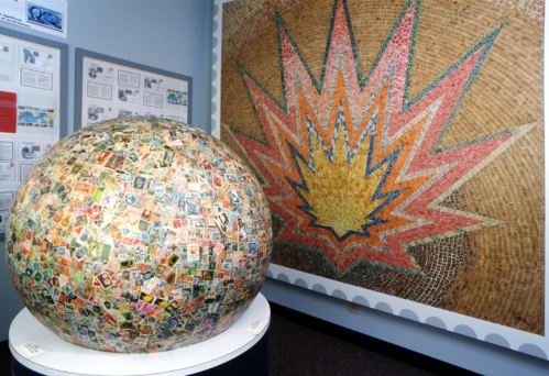 A large globe covered in colorful stamps, next to a vibrant starburst mural on the wall.