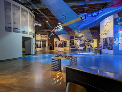 A museum interior featuring a suspended airplane, historical photos, and exhibits on aviation history.