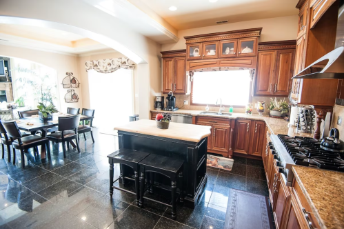 A spacious kitchen with wooden cabinets, a central island, and a dining area featuring a large table and chairs.