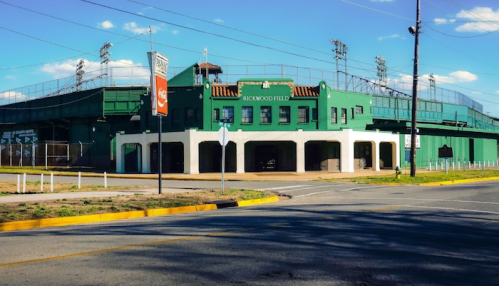 A green sports stadium named Rockwood Field, featuring a multi-level structure and surrounding street.