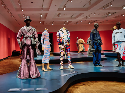 Fashion exhibition featuring diverse mannequins in vibrant, contemporary outfits against a pink backdrop.