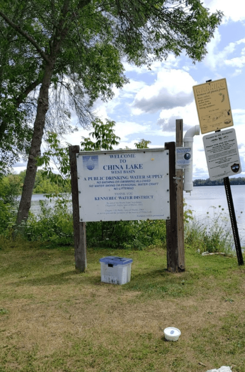 Sign at China Lake indicating it's a public drinking water supply, with trees and water in the background.