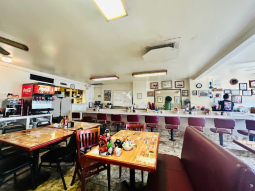 A cozy diner interior with wooden tables, a counter, and vintage decor on the walls.