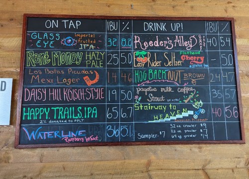 Chalkboard menu listing various beers on tap with prices and descriptions, including "Rent Money Hazy Pale" and "Waterline Raspberry Wheat."