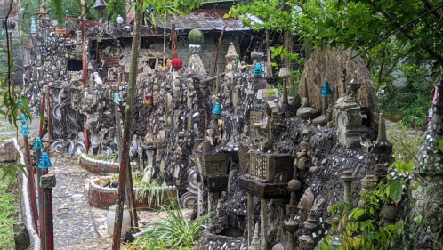 A whimsical garden filled with unique sculptures and decorations made from stones and various materials.